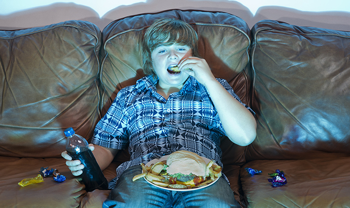Boy watching TV eating junk food