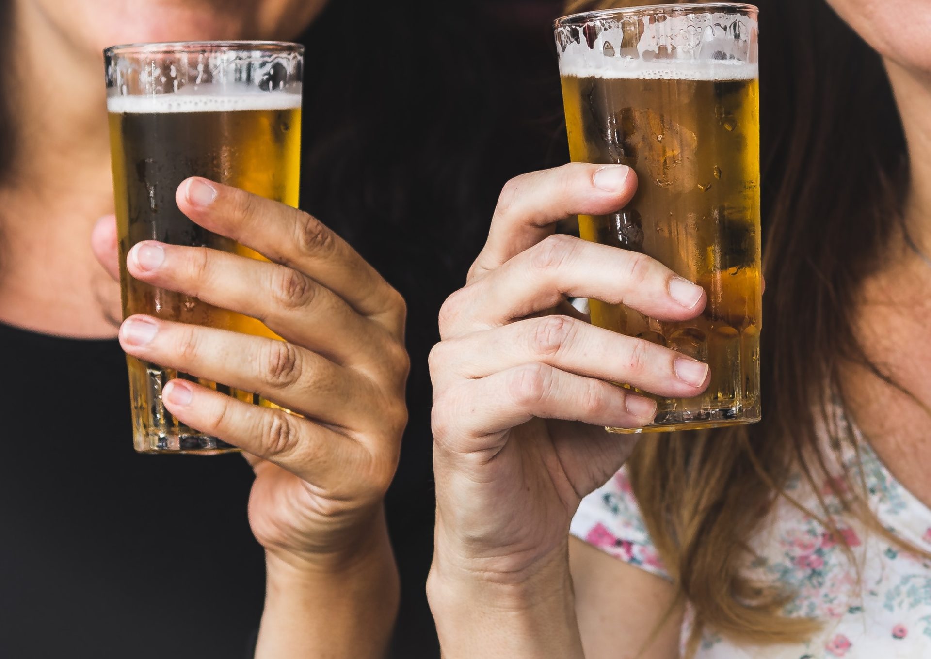 two people holding beer glasses