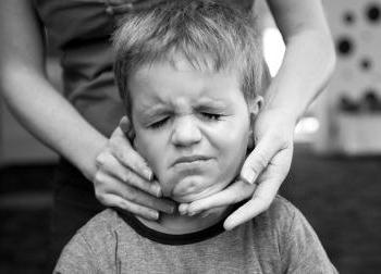 A mother applies sunscreen to a boy who grimaces