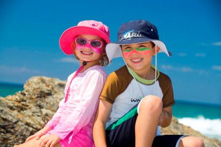 Two children in hats, sunglasses and long beachwear