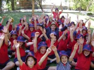 school children raise their hands to the air in celebration
