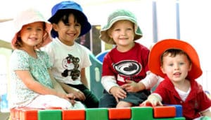 happy kids in hats Children sit together in a childcare centre