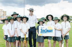 a teacher and some children hold a cricket bat and a SunSmart sign