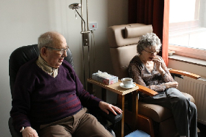 Elderly couple sitting down at a nursing home.
