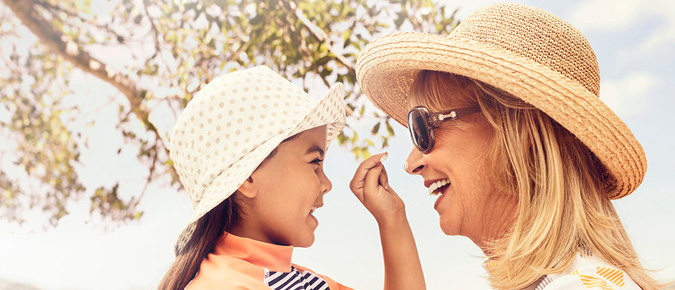 A girl applies sunscreen to her mother's nose