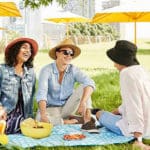 Group of people sitting on picnic mat in the park.