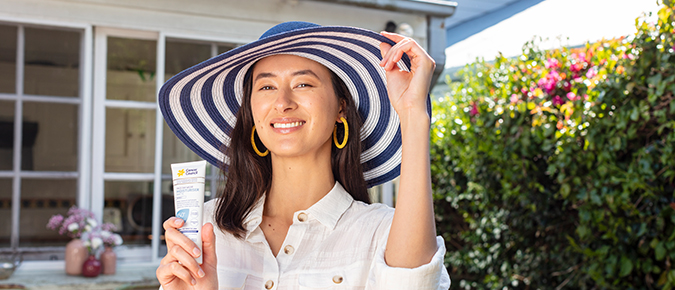 Woman wearing a hait and holding sunscreen