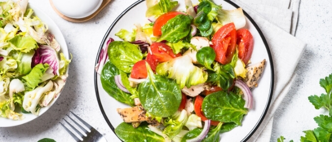 Two plates of leafy salads on table