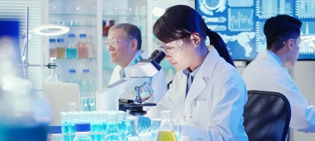 Asian scientist looking in a microscope.