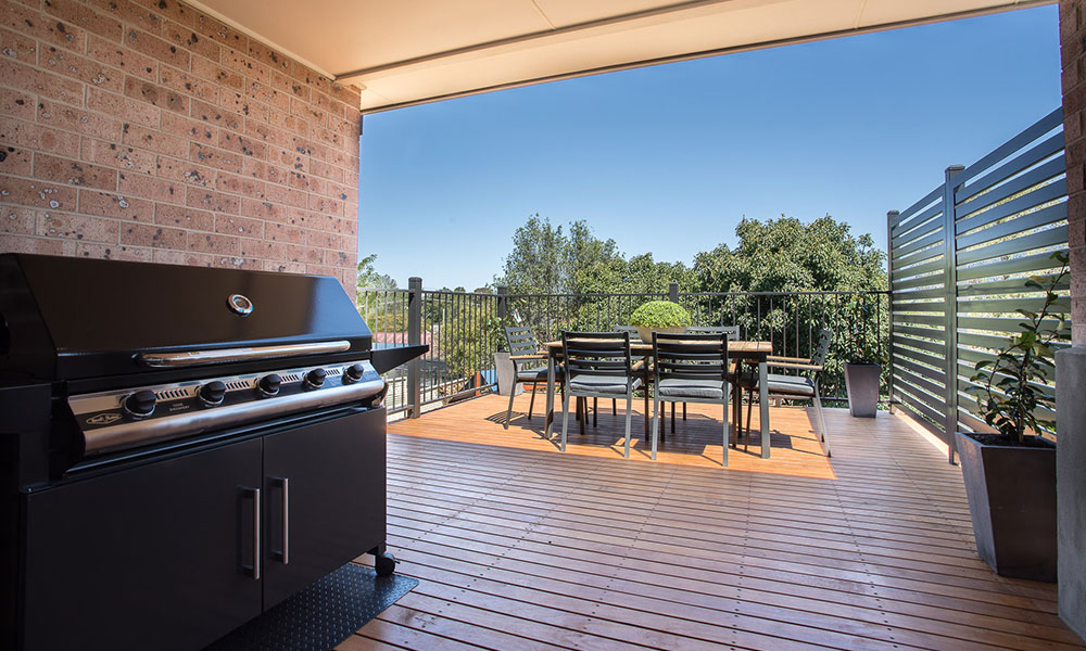 A large barbecue in front of an outdoor dining setting