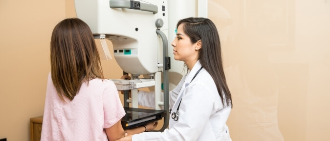 Doctor conducting a mammogram on a patient. 