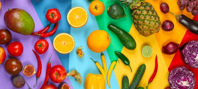 Assorted fruit and vegetables on a rainbow background.