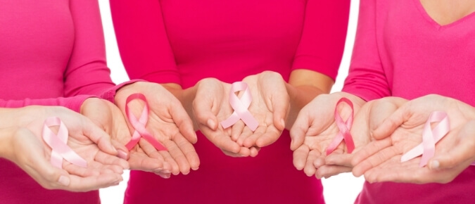 Three women holding pink ribbons