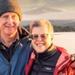 Middle aged man and woman posing in front of a scenic background.