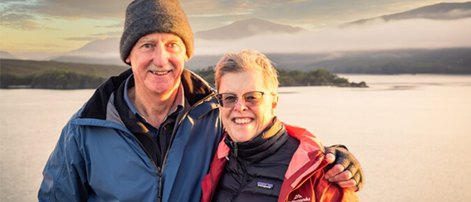 Middle aged man and woman posing in front of a scenic background.