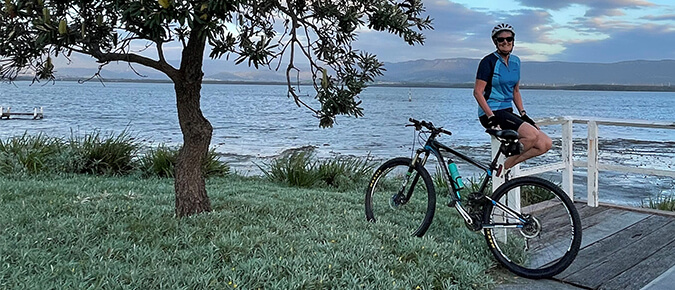 Woman wearing helmet standing next to a bike. 