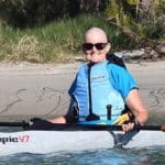 Bald woman wearing sunglasses on a kayak.