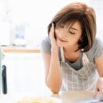 Asian woman looking at her airfryer.