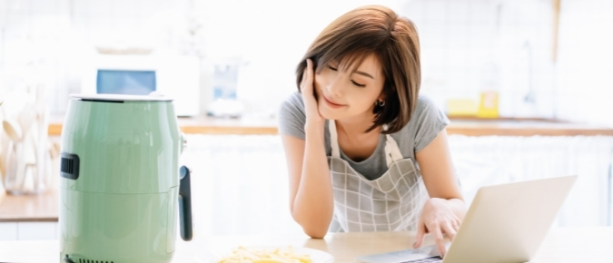 Asian woman looking at her airfryer.