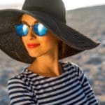 Attractive woman wearing hat and sunglasses at the beach.