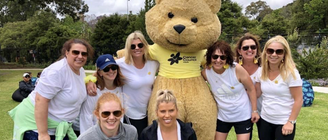 Eight women and a large teddy bear.