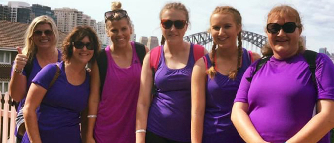 Six women wearing purple smiling.
