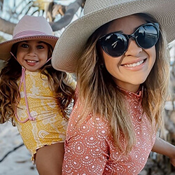 Woman wearing sunglasses with a little girl on her back. 