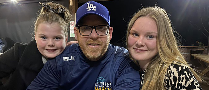 Man and two young girls smiling.