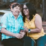 two women sitting on bench laughing