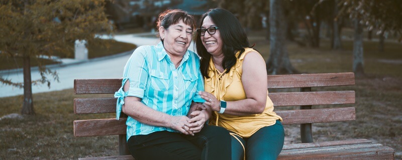 two women sitting on bench laughing