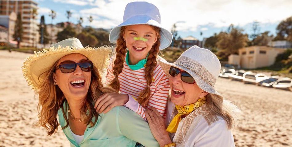 Woman wearing a hat and holding sunscreen.