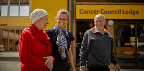 two women and a man outside cancer council lodge smiling