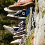 young adults wearing converses feet dangling off a cliff