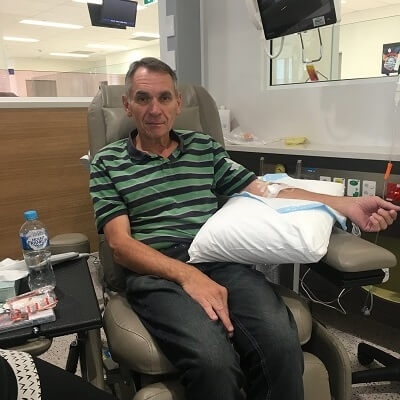 John is pictured receiving treatment for pancreatic cancer, sitting in a hospital chair,
