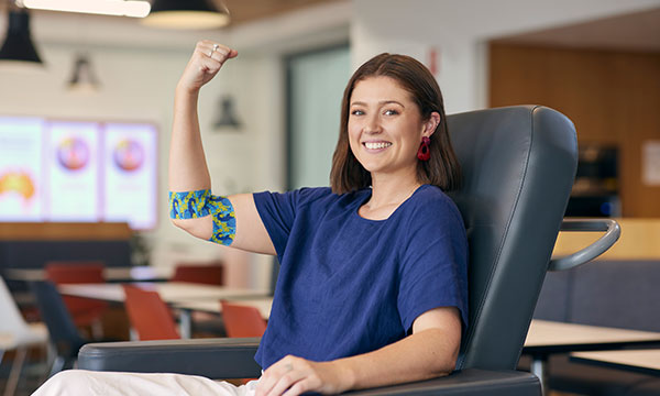 A young woman proudly shows her bandage after a blood donation