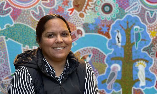 Emma Hickey in front of an Aboriginal artwork