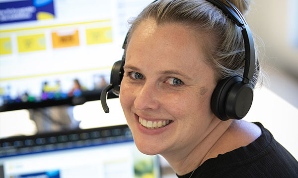 Erin, smiling wearing a telephone headset