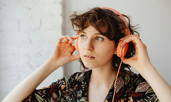 A young woman adjusts her headphones