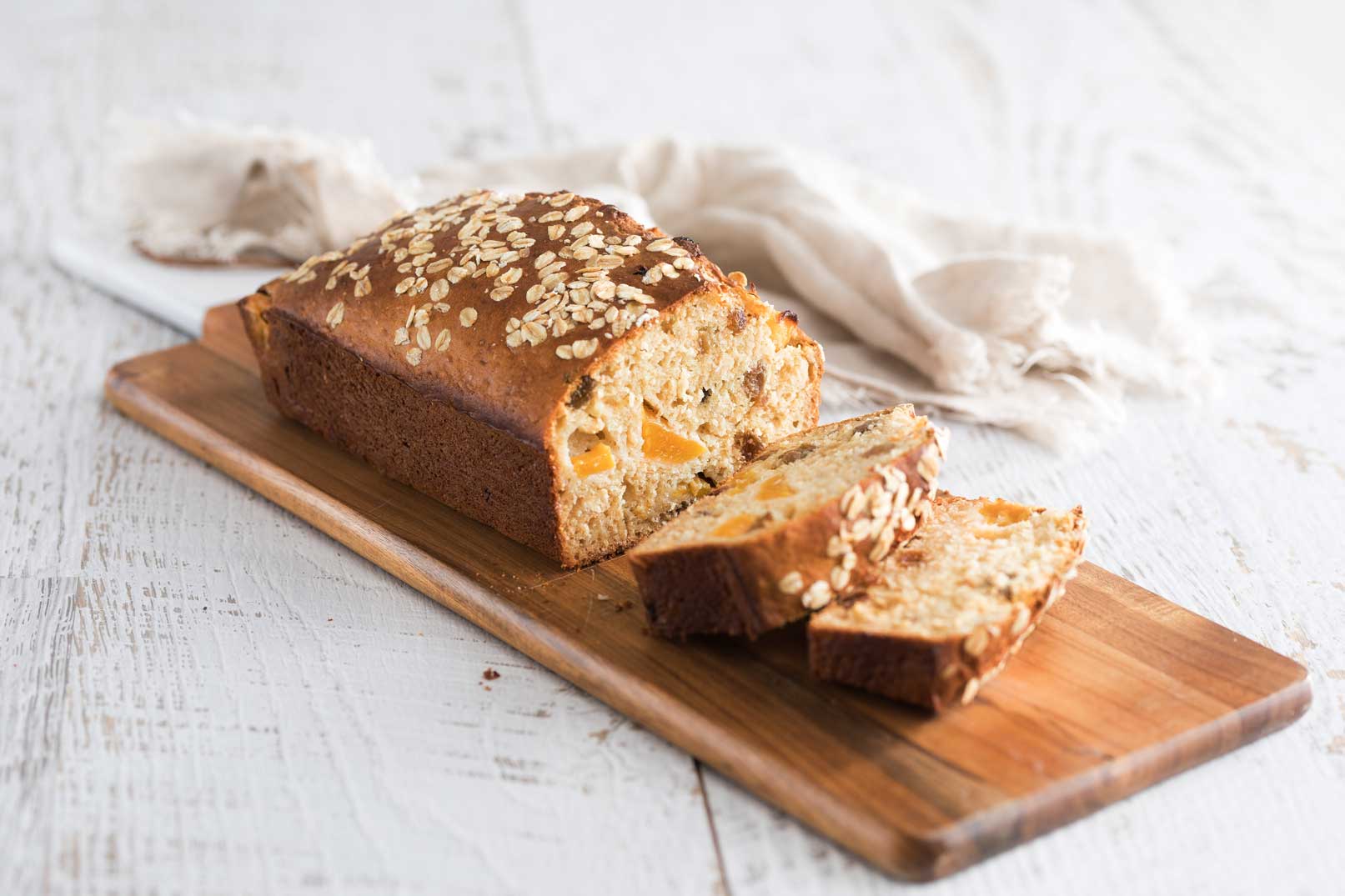 A photo of oat, sultana and peach bread served on a wooden serving board.