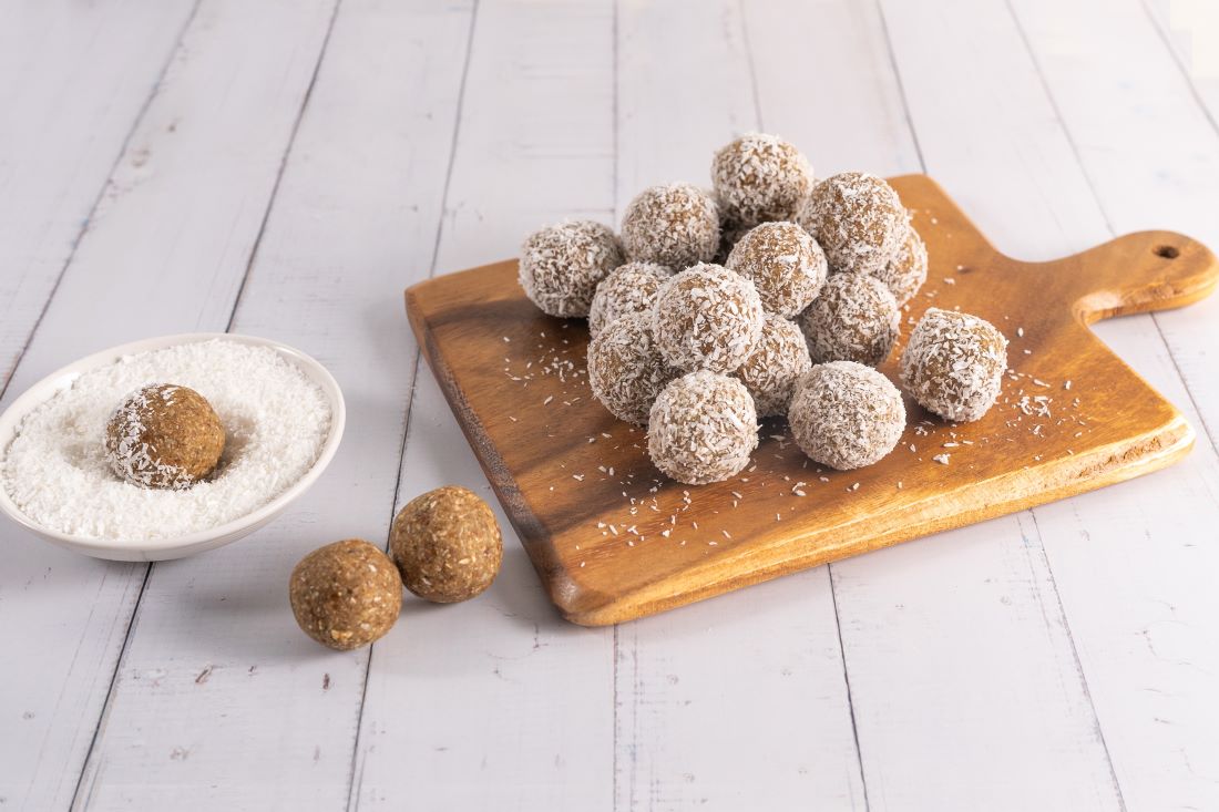 A photo of sultana coconut bliss balls on a wooden serving board.