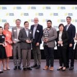 The recipients of the 2025 Cancer Council NSW research awards stand holding their awards in front of a Cancer Council media backdrop.