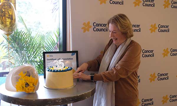 Alison slices a cake with candles showing the number 35