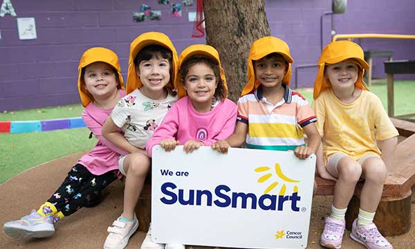 Five primary school students hold a sign saying We are SunSmart