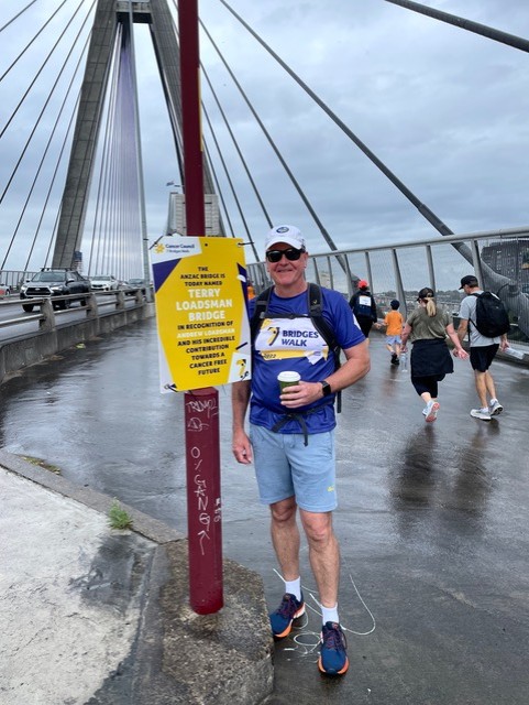 Andrew Loadsman beside a Seven Bridges Walk bridge sign dedicated to his father, Terry.