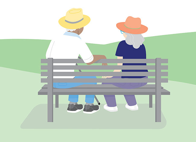 Two people sitting on a park bench, seen from behind. One has a cane.